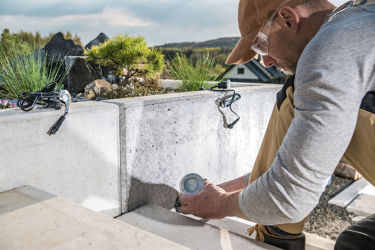 A person Installing Outdoor Stairs Spotlight in a cement wall. Exterior Ligting