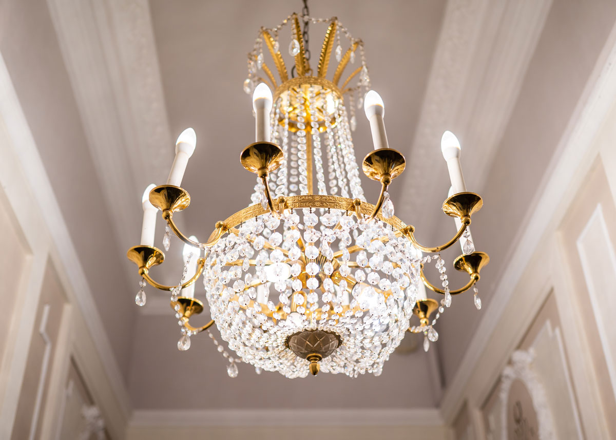 Luxury chandelier hanging in the corridor of a house. Crystal Chandelier in Brass Finish.