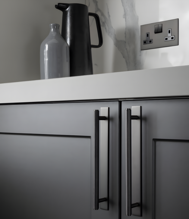 Close-up of industrial style knurled cabinet pull handles in a Matt Bronze finish with rectangular backplates on dark grey kitchen doors.